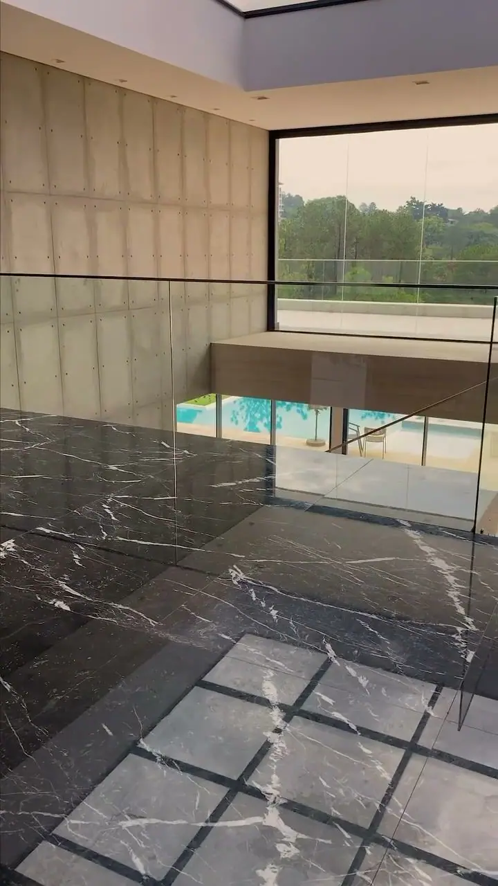 Piso em mármore preto com veios brancos aplicado pela equipe da G2M, com vista para a piscina