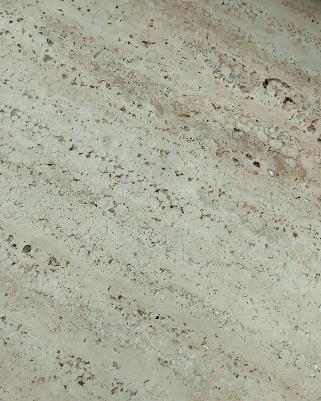 Textura do Travertino Romano em close, com veios horizontais e poros naturais